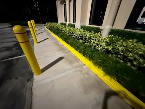 Yellow bollards and a painted planter curb lit at night
