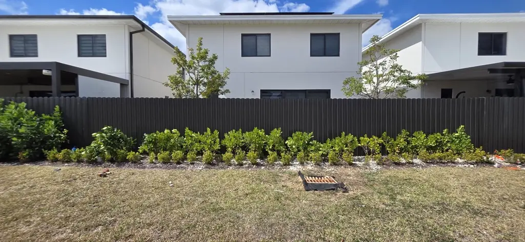 Finished black metal fence along a townhome with planting beside it